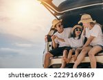 Happy Family Day. Dad, mom and daughter enjoying road trip sitting on back car, Parents and children traveling in holiday at sea beach, family having fun in summer vacation on beach with automobile