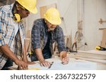 Small photo of Two carpenter man wear helmet meeting planning job together at carpentry workshop, craftsmen talking checklist and plan on blueprint paper in woodshop, teamwork, National Carpenters Day