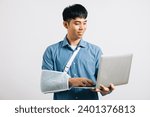 Small photo of Despite a broken arm, an Asian businessman uses a splint and a laptop, symbolizing his commitment to work. Studio shot isolated on white background, highlighting resilience and recovery.