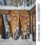 Small photo of Classic wooden snowshoes (Huron) on a wooden deck in a backyard covered by snow