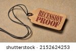 Small photo of recession proof - red stencil text on a paper price tag against textured paper, marketing slogan