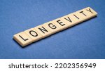 Small photo of longevity word in ivory letter tiles against textured handmade paper, lifespan and healthspan concept