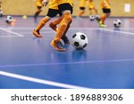 Indoor football training for youth team. Young boys with soccer balls running on wooden parquet. Indoor football soccer school practice. Kids in soccer sportswear