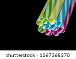 Small photo of Colourly striped plastic drinking straws, black underground background