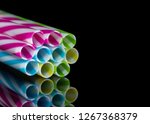 Small photo of Colourly striped plastic drinking straws bundled, black mirroring underground background