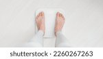Small photo of Female bare feet standing on a scales