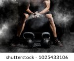 Weightlifter clapping hands and preparing for workout at a gym. Focus on dust