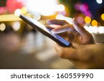 Woman using her Mobile Phone in the street, night light Background