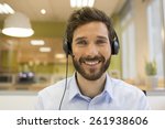 Happy Businessman in the office on the phone, headset, Skype. looking camera
