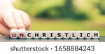Small photo of Hand turns dice and changes the German word "unchristlich" ("unchristian") to "christlich" ("christian").