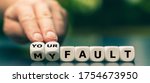 Small photo of Hand turns dice and changes the expression "my fault" to "your fault".