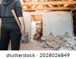 Small photo of Construction worker with a sledge hammer after demolishing a brick wall in a private home.