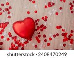 On wooden laminate floor lies red foil heart shaped balloon among red, white rose petals. Greeting card, place for dough, copy space, mock up. Top view of Valentines Day decorations, Mothers day