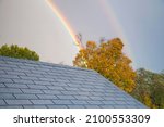 A double rainbow rising above a rooftop in torrington connecticut on an autumn day.