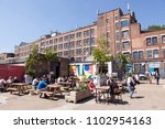 Small photo of PECKHAM, UK - MAY 19, 2018: People drinking and hanging around outside a bar in the trendy Copeland Park in South London. The Bussey Building is in the background.