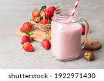 Glasses of fresh strawberry smoothie on a grey background. Summer drink shake, milkshake and refreshment organic concept.