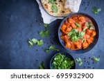 Traditional Indian/British dish chicken tikka masala background. Spicy chicken tikka masala/curry in bowl, indian bread naan, fresh cilantro. Indian style dinner. Space for text. Top view. Indian food