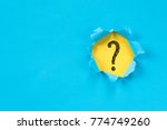 blue torn paper revealing question mark symbol on yellow paper. question mark background