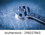 Small photo of Stainless hook wrench on scratched metallic background close up view construction concept.