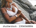 Photo of beautiful boho styled model wearing white swimsuit and silver bohemian jewelery on the beach in sunset