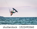 Small photo of kiteboarder kitesurfing unhooked at sunset and jumping rotations