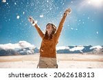 Happy young girl is tossing the snow in mountains. Winter vacations concept