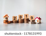 Wooden block year 2019 and mini house on stack coins using as business and financial concept
