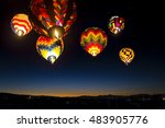 Colorful hot air balloons at dawn lit up in the sky.