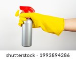 Cleaning concept - woman hand in yellow rubber protective gloves hold cleaning agent bottle isolated on white background. Cleaning Service Worker.
