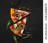 Small photo of Pizza slices with rocket salad on black background, top view