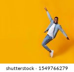 Small photo of Funny african american man posing on tiptoes over yellow background in studio