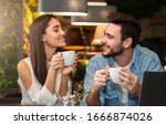 Small photo of Dating. Young couple tasting coffee drinks enjoying flirt and conversation during weekend date sitting in cozy cafe