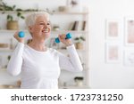 Healthy Lifestyle. Smiling Senior Lady Exercising With Dumbbells At Home, Free Space