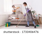 Small photo of Residential Cleaning Services. Couple Of Skilled Housekeepers Man And Woman Tidying Up Apartment, Doing Household Together, Free Space