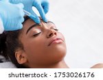 Plastic surgery. Young african woman receiving botox injection in interbrow zone at beauty clinic, closeup, copy space