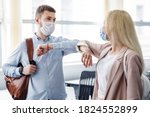 Small photo of Say hello and greet, social distance and return to work after quarantine. Millennial man and woman in protective masks are touched by elbows in interior of office during COVID-19 epidemic, free space