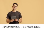 Small photo of Teacher, tutor, blogger or student. Cheerful young attractive man in glasses looks at camera, holds digital tablet on online lesson, isolated on light background, panorama, empty space, studio shot