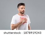 Breathing problem. Sick middle-aged man with chest pain touching inflammated zone and looking at copy space, grey studio background. Bearded man suffering from pneumonia or asthma. COVID-19 concept