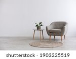 Modern interior design with light empty mock-up wall and gray furniture, loft and vintage of living room. Armchair, table with green plant in pot, round carpet on floor, on white wall background