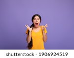 Unbelievable. Portrait of excited overjoyed and shocked young indian woman looking at camera and spreading hands, expressing surprise, screaming with open mouth isolated over purple background