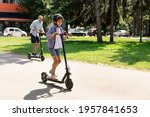 Happy Loving Family. Full body length photo of excited curly boy in protective helmet driving motorized push scooter with daddy at park, spending time together outdoors at summer, selective focus