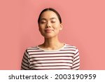 Closeup Portrait Of Calm Asian Woman Standing With Closed Eyes On Pink Background, Pleased Millennial Korean Female In Striped Shirt Feeling Relaxed And Happy While Posing In Studio, Copy Space