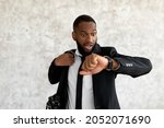 Hurry Up To Work. Portrait of shocked worried black business man with open mouth looking at wrist watch, African American male wearing suit scared of being late to meeting, rushing to office workplace