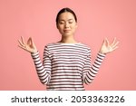 Zen. Relaxed Peaceful Asian Woman Meditating With Closed Eyes, Calm Young Korean Female Practicing Yoga, Keeping Hands In Mudra Gesture, Standing Isolated Over Pink Background, Copy Space