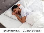 Small photo of Asleep young arab man sleeping, resting peacefully in comfortable bed, lying with closed eyes, free space. Recreation, deep male sleep, time to rest and nap concept