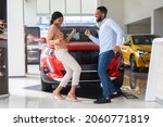 Small photo of Overjoyed Black Couple Celebrating Buying New Car, Dancing In Dealership Office. Happy African American Spouses Having Fun In Auto Salon, Emotionally Reacting To Automobile Purchase, Free Space