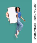 Small photo of Full length of cheery Asian woman jumping and smiling, showing cellphone with empty space for mobile app or website on screen, turquoise studio background, mockup. Creative collage