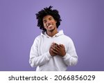Kind African American teenager placing hands on his heart, expressing love and affection on violet studio background. Friendly black teen guy showing romantic feelings or kindness
