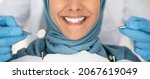 Small photo of Dental Check Up. Closeup Shot Of Smiling Muslim Lady Getting Treatment In Stomatologic Clinic, Dentist In Blue Gloves Examining Teeth Of Islamic Lady In Hijab, Using Sterile Dental Tools, Cropped