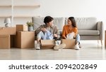 Small photo of Relocation day concept. Cheerful millennial Asian couple unpacking belongings and having conversation, moving to new apartment or their own house, copy space. Panorama